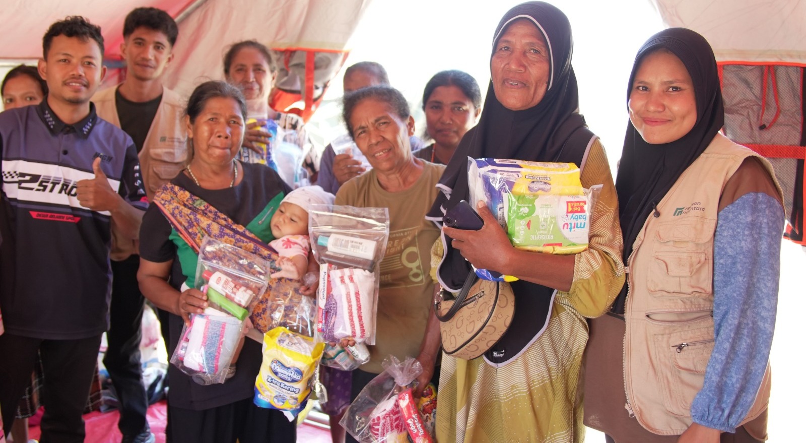 Ibu-ibu penyintas bencana menerima bantuan paket kebutuhan bayi dan anak dari relawan.
