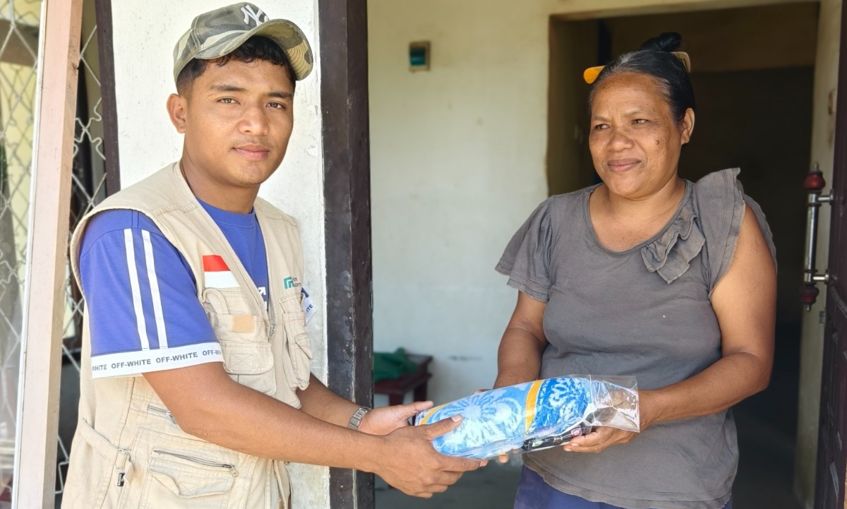 Relawan menyerahkan bantuan selimut dan pakaian kepada seorang ibu penyintas bencana.