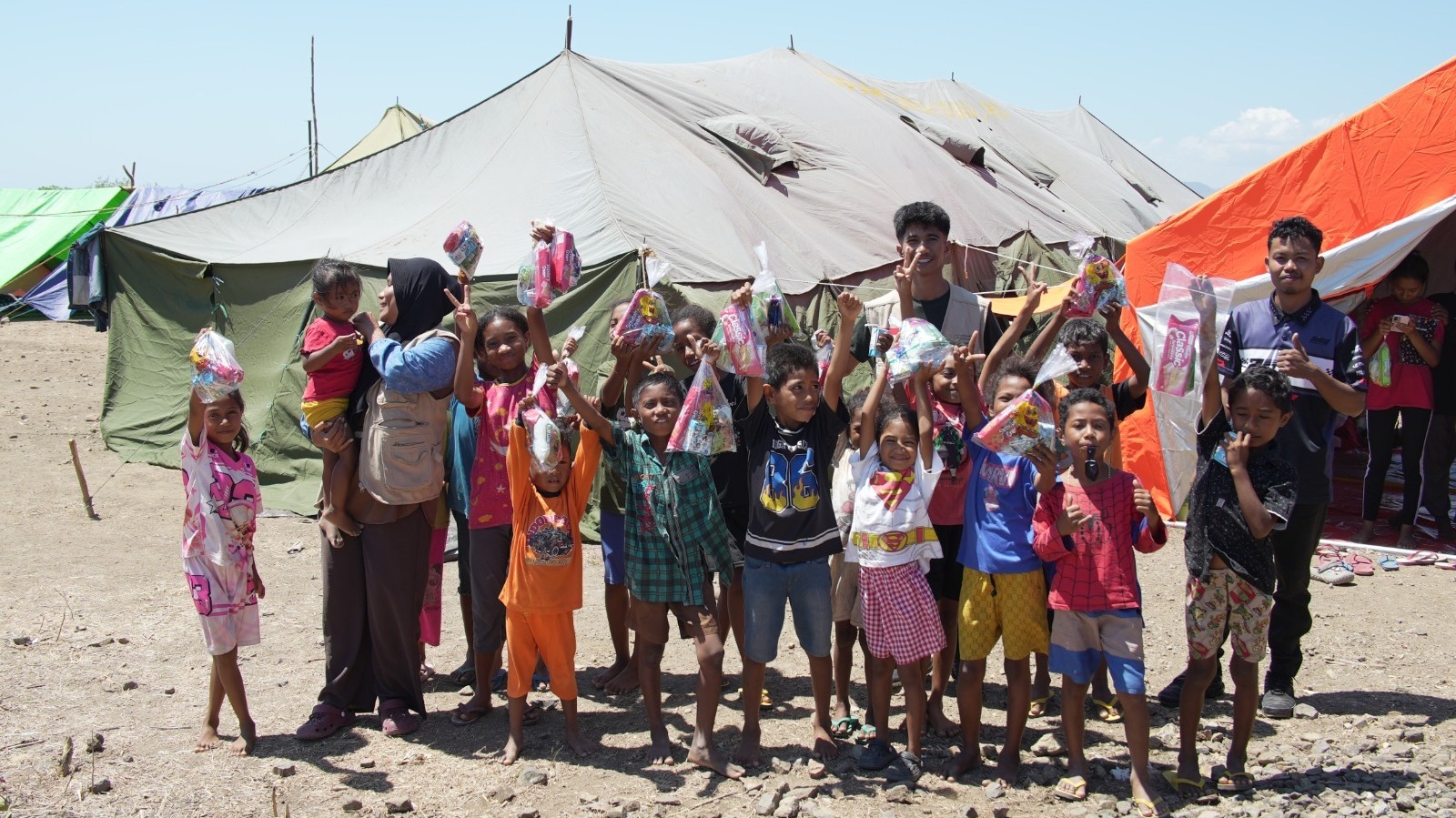 Foto bersama relawan dan anak-anak penyintas bencana di depan tenda pengungsian setelah penyaluran bantuan.