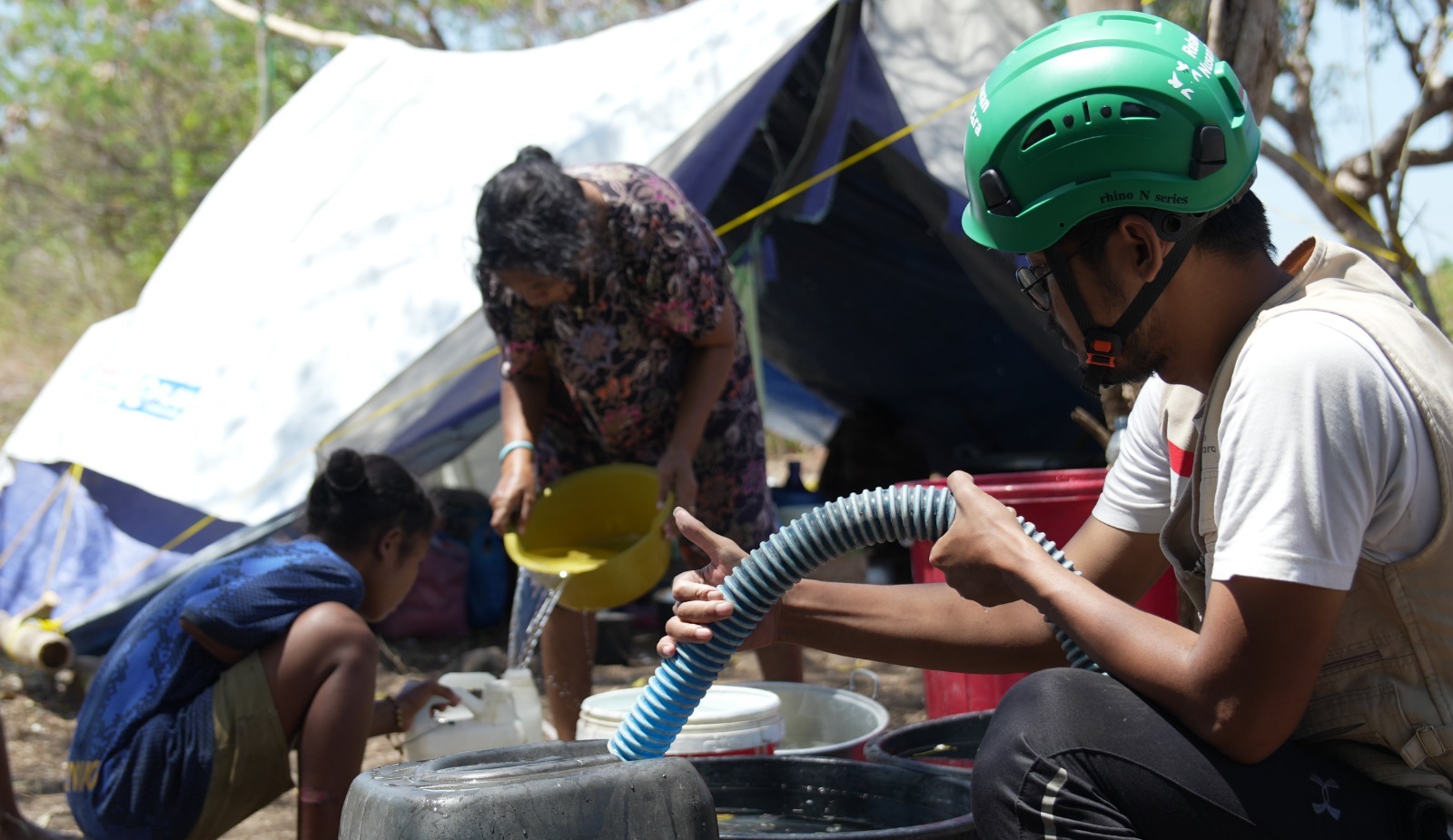 Relawan menyalurkan bantuan air bersih untuk penyintas bencana di area pengungsian.