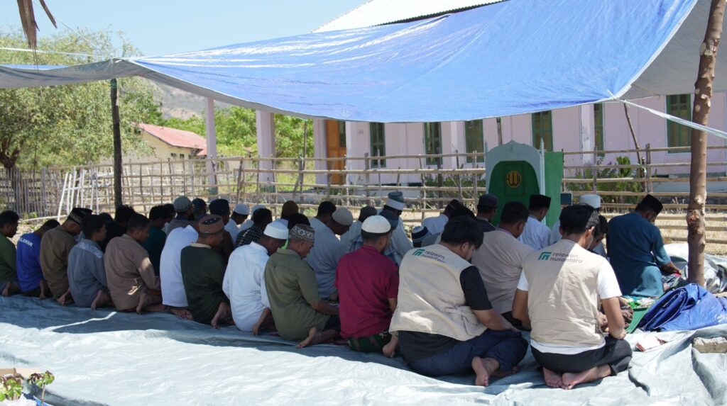 Warga Desa Waekokak melaksanakan shalat Jumat berjamaah di bawah tenda terpal darurat pascagempa Nagekeo, didampingi relawan.