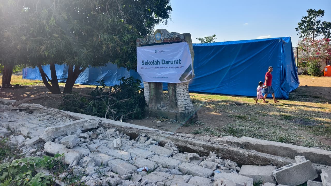 Kondisi luar lokasi sekolah darurat SDI Lengkosambi dengan tenda terpal biru di area terdampak bencana.