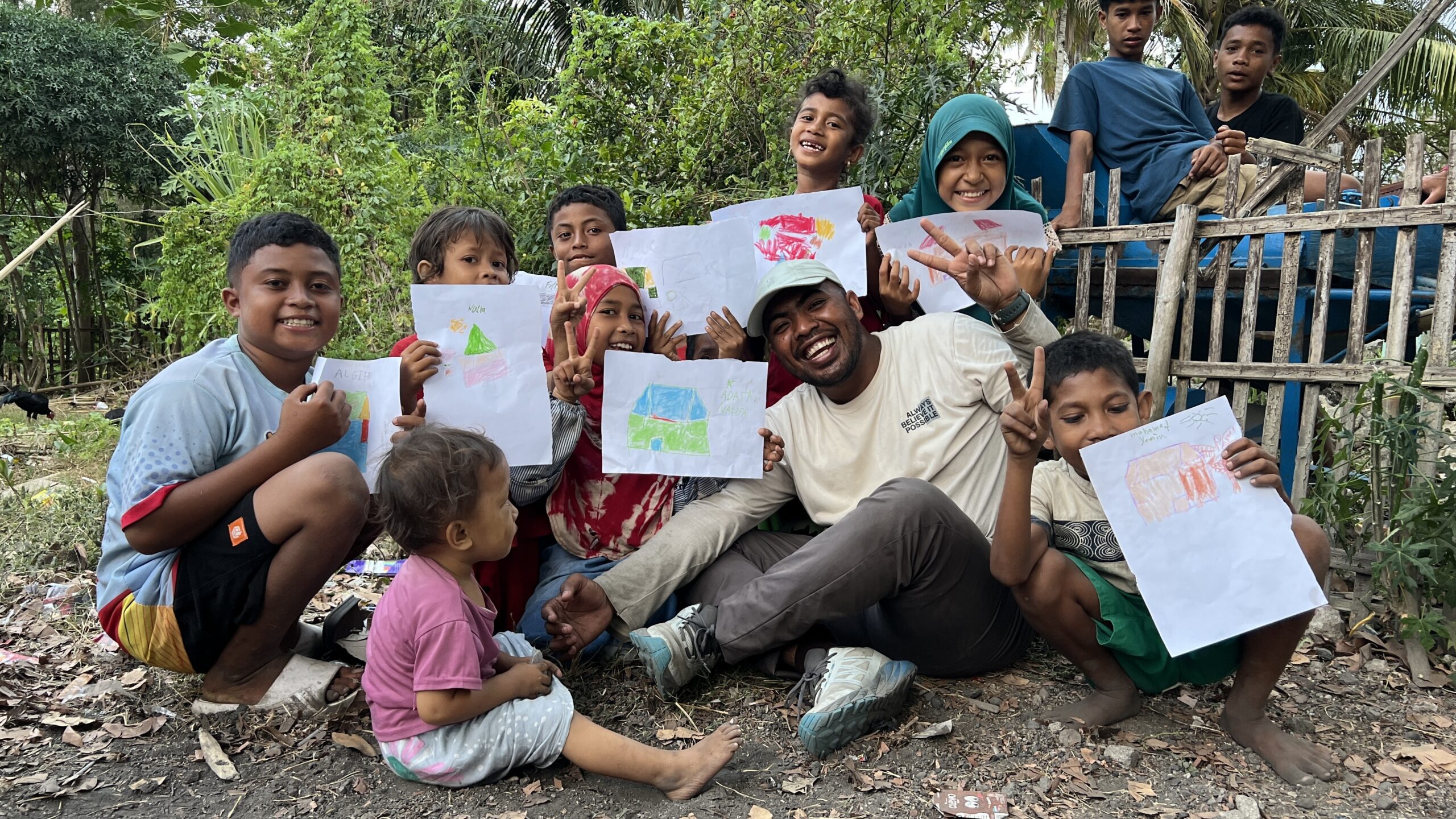 Momen kebersamaan relawan dan anak-anak desa yang memegang hasil karya mewarnai dalam program dukungan psikososial Relawan Nusantara.