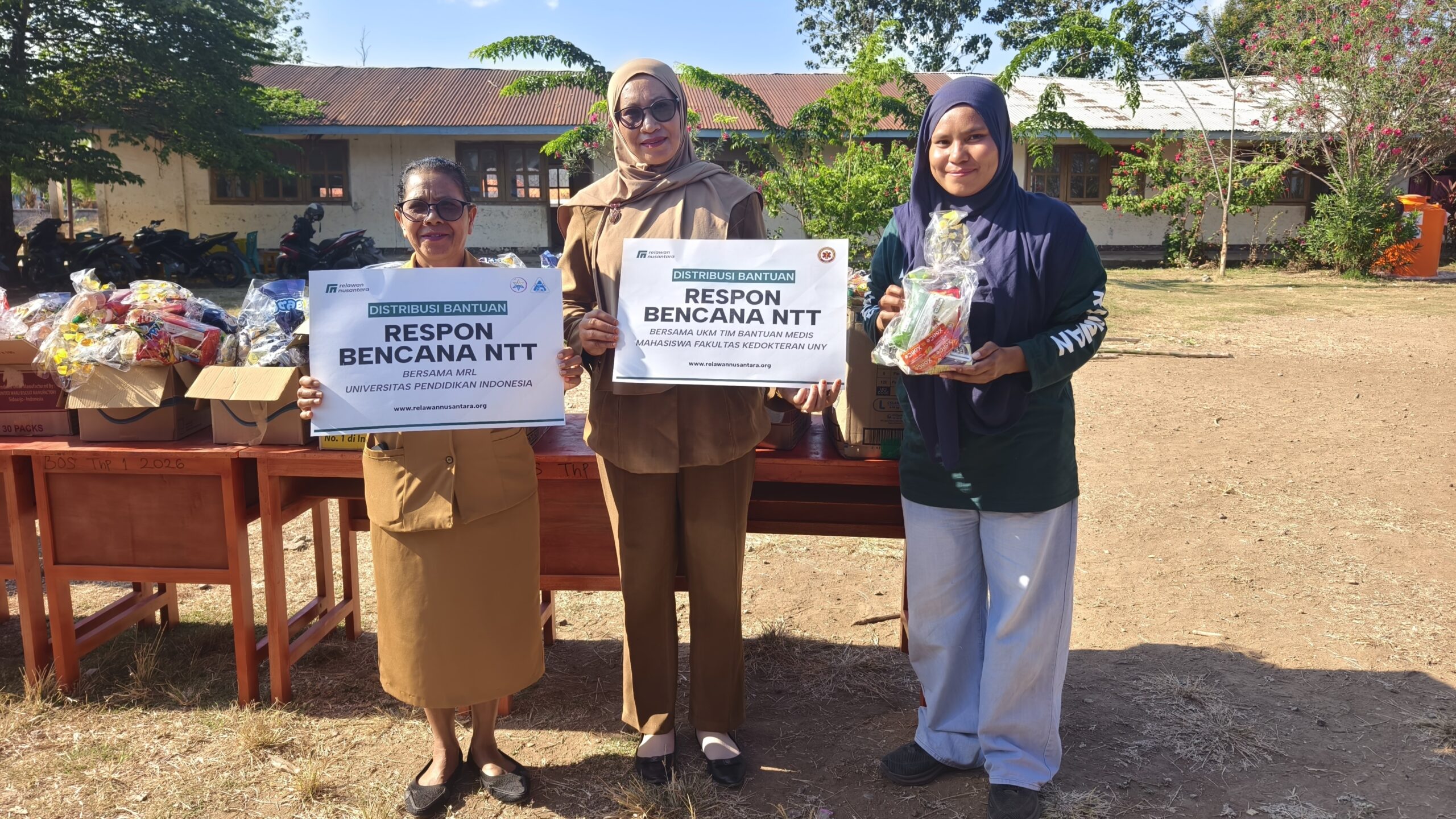 Perwakilan sekolah dan Relawan Nusantara memegang papan serah terima bantuan PMT FK UNY dan MRL UPI.