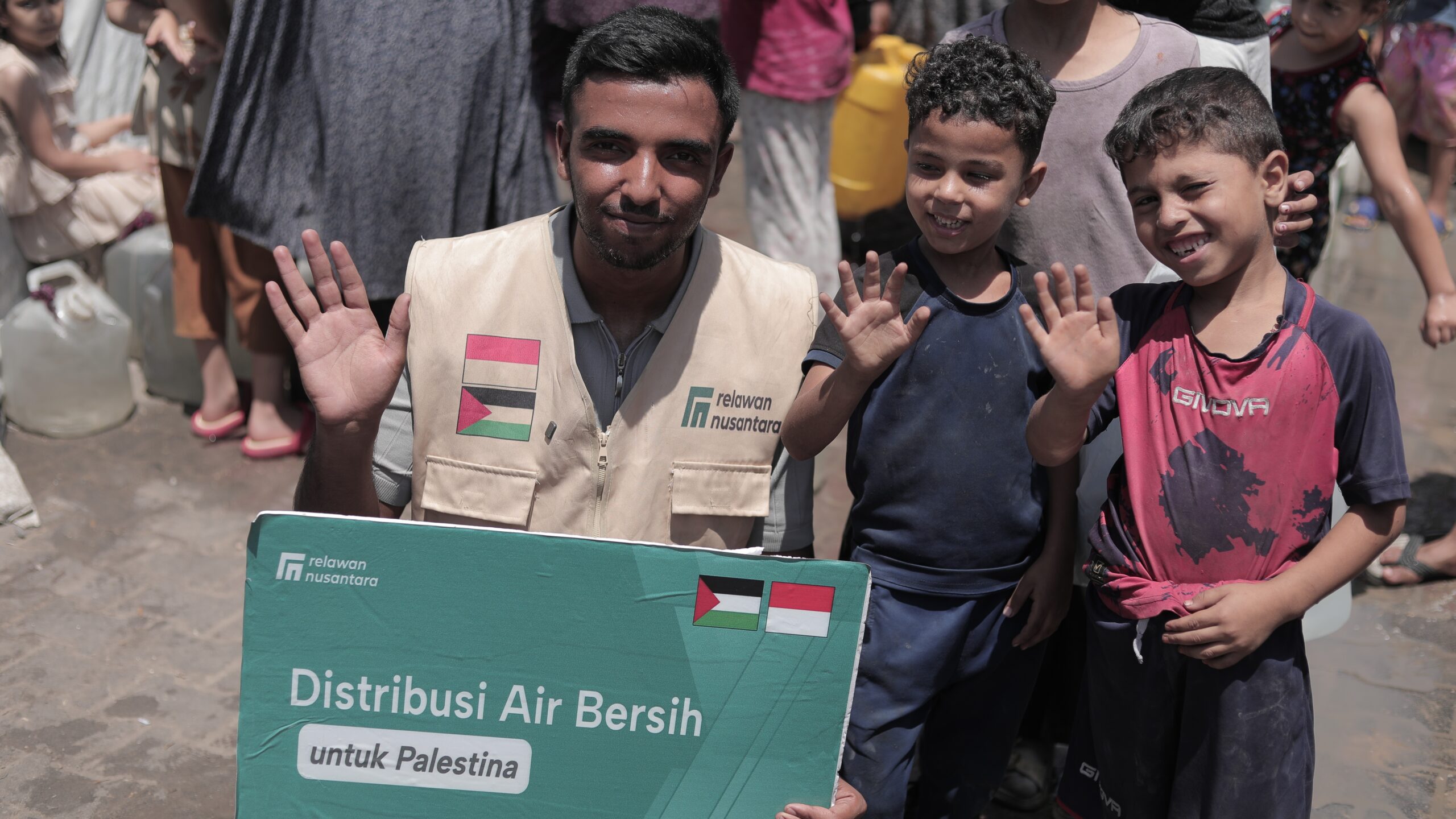 Relawan Nusantara bersama anak-anak Palestina membentangkan papan informasi bantuan air bersih di Gaza.