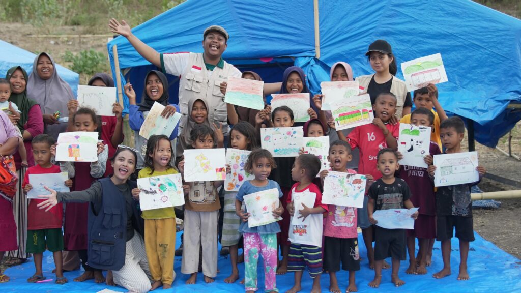 Relawan Nusantara bersama anak-anak korban bencana di NTT ceria memamerkan hasil gambar di posko pemulihan.