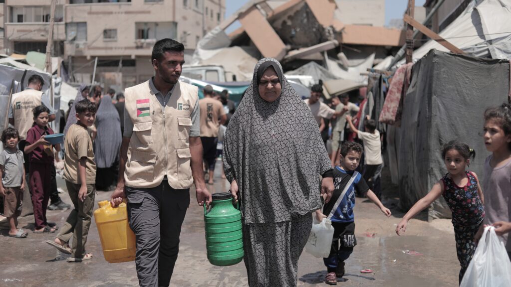Relawan Nusantara membantu seorang ibu pengungsi membawa jerigen air bersih di Gaza.