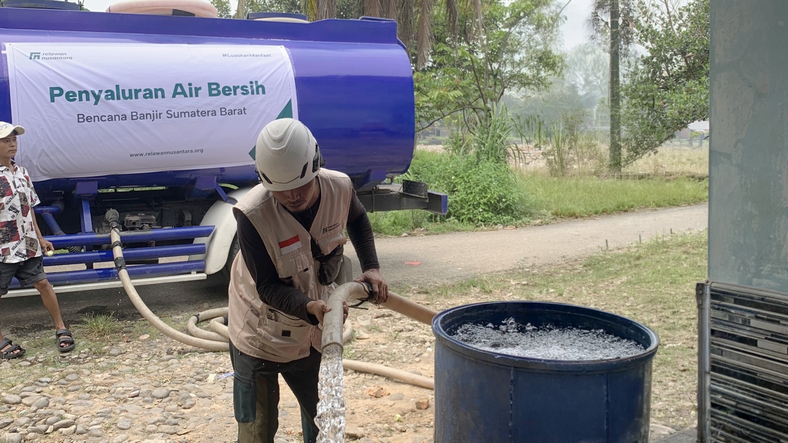 Petugas Relawan Nusantara mengisi drum penampungan air bersih warga menggunakan selang dari truk tangki di Padang.