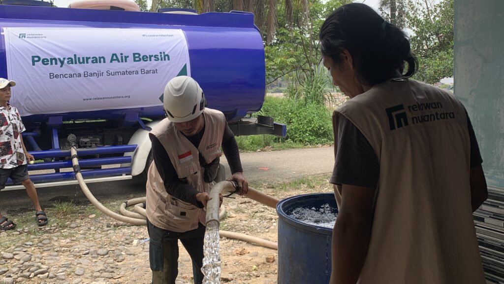 Petugas Relawan Nusantara mengisi drum penampungan air bersih warga menggunakan selang dari truk tangki di Padang.