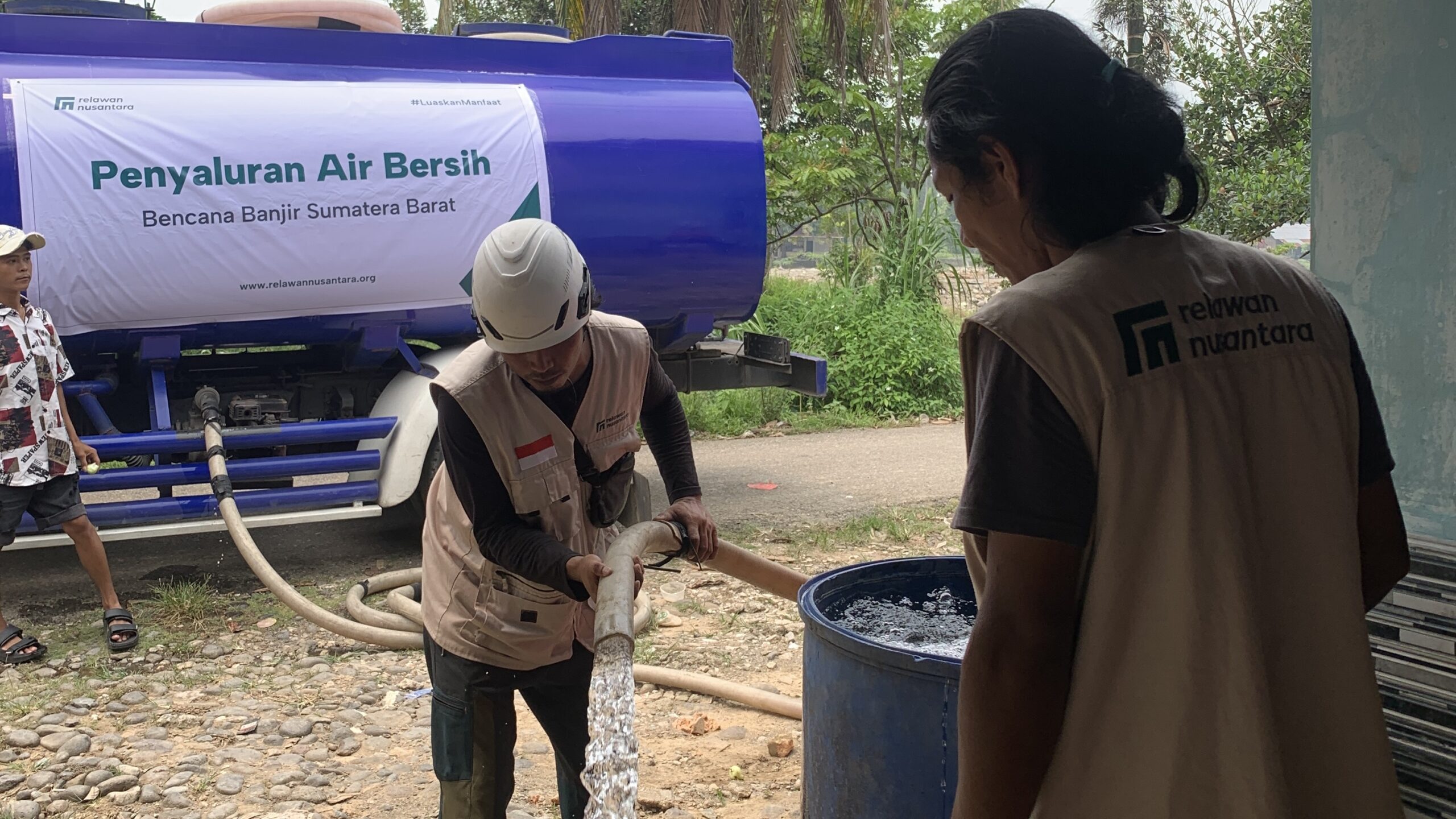 bantuan-air-bersih-relawan-nusantara-sumbar Petugas Relawan Nusantara mengisi drum penampungan air bersih warga menggunakan selang dari truk tangki di Padang.