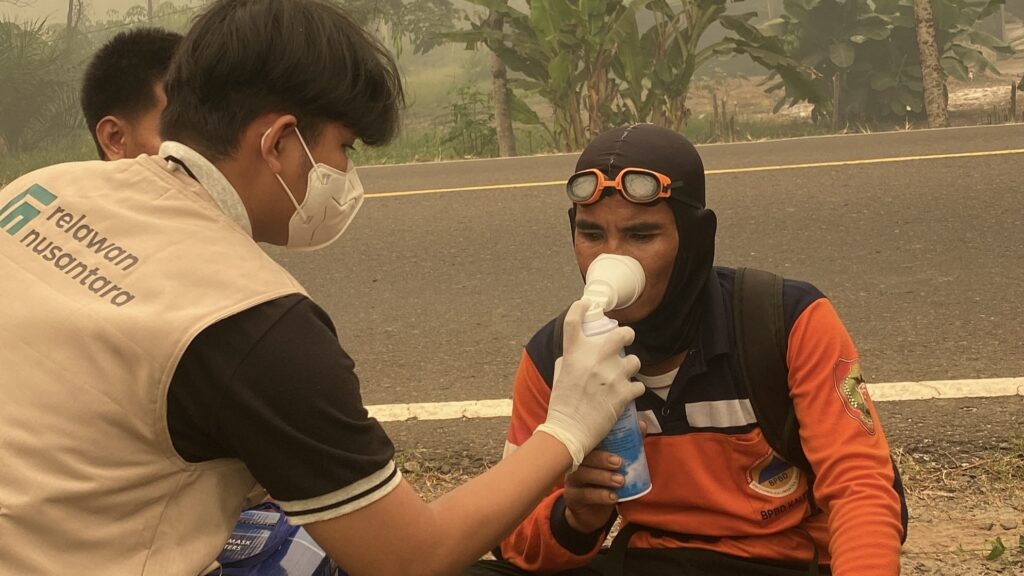 Tim medis membantu penggunaan tabung oksigen portabel bagi petugas BPBD di pinggir jalan kawasan karhutla Palangka Raya.