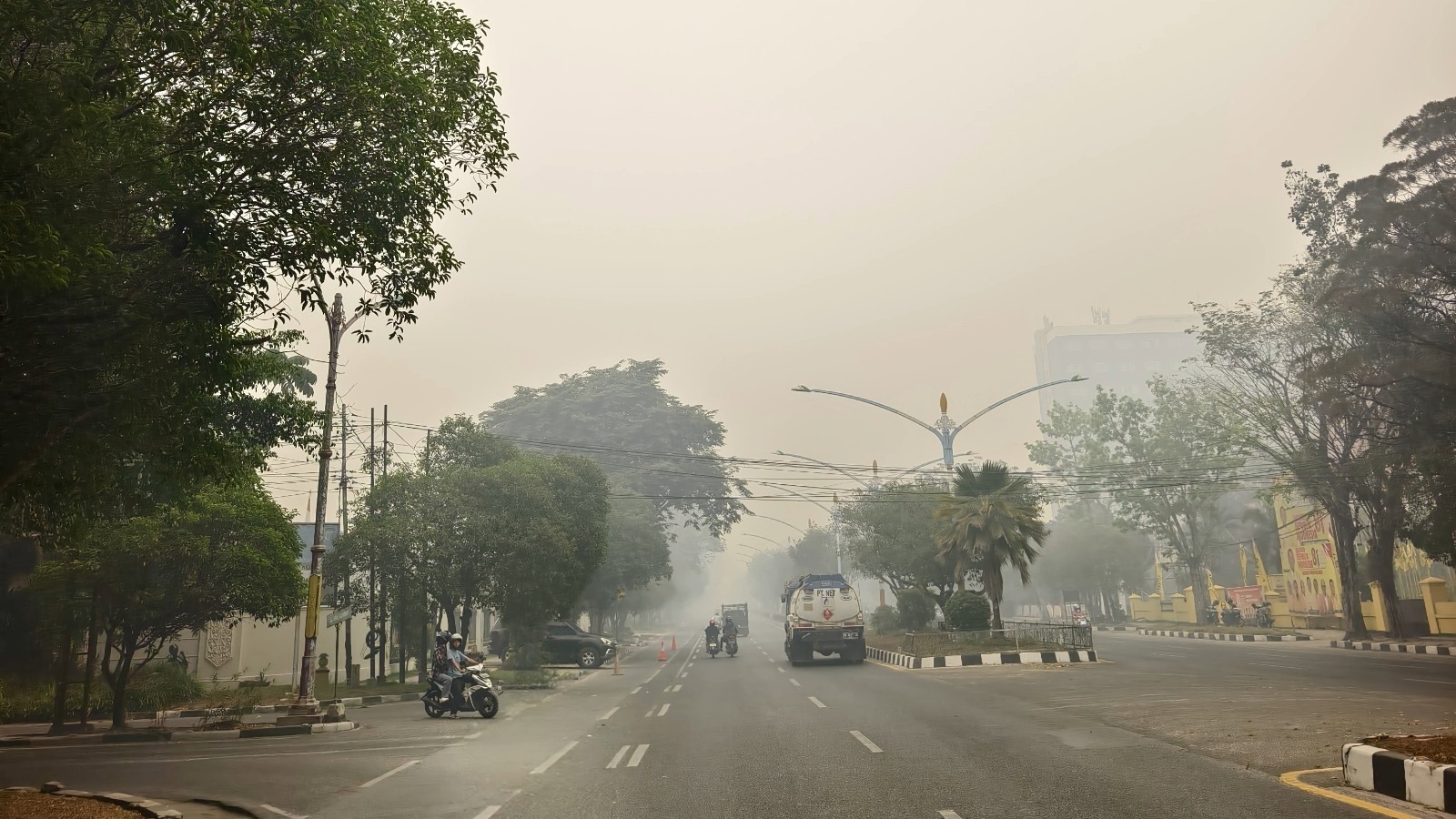 Kondisi jalanan kota yang tertutup kabut asap pekat akibat karhutla, memperlihatkan para pengendara dan relawan di tengah kualitas udara buruk.