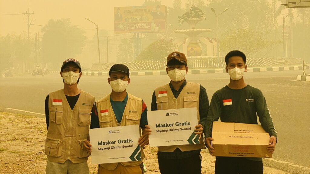Empat tim Relawan Nusantara memegang papan aksi pembagian masker gratis akibat karhutla di Bundaran Besar Palangka Raya.